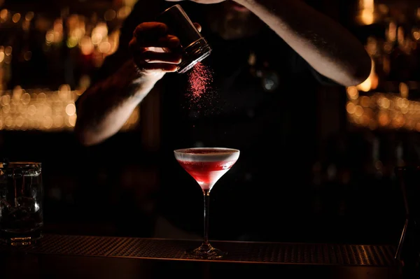 Barman masculino adicionando a um coquetel com um chantilly um pó vermelho — Fotografia de Stock