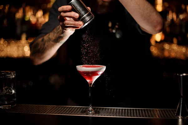 Profesjonalny barman dodając do koktajlu z bitą śmietaną czerwony proszek w ciemności — Zdjęcie stockowe