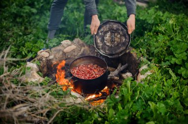 Adam bir kamp ateşi üzerinde kaynatma pot kapatır