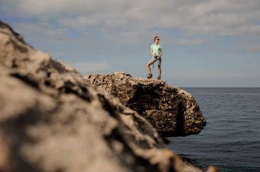 Deniz kıyısındaki kayaların üzerinde duran genç kadın