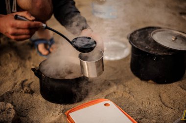 Adam bir metal bardak çorba dökülen