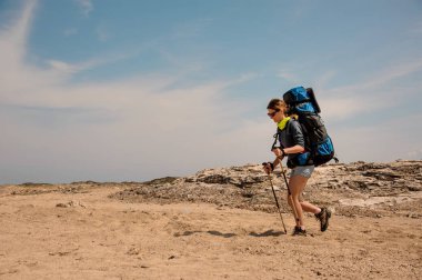 Bir çölde sopalarla yürüyen genç kadın