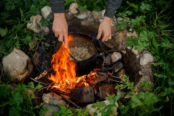 Yakın çekim adam kamp ateşi bir tencerede gıda hazırlanıyor