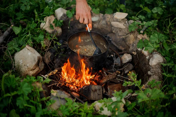 Kamp ateşi üzerinde Pan adam karıştırma gıda yakın çekim