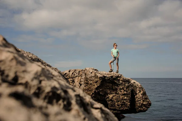 Ung flicka som står på klipporna nära havet — Stockfoto