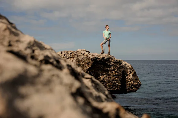 Deniz kıyısındaki kayaların üzerinde duran genç kadın
