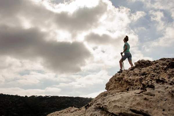 Молода дівчина стоїть на каменях біля пагорбів — стокове фото