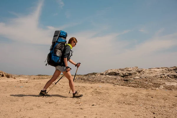 Unga kvinnliga vandrare reser med pinnar i en öken — Stockfoto