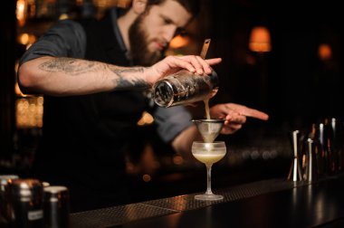 Barmen shaker ve elek kullanarak bir alkol kokteyl hazırlar