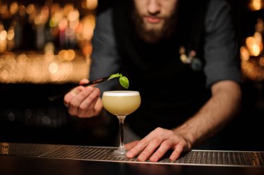 Barmen forceps kullanarak nane ile kokteyl hazırlar