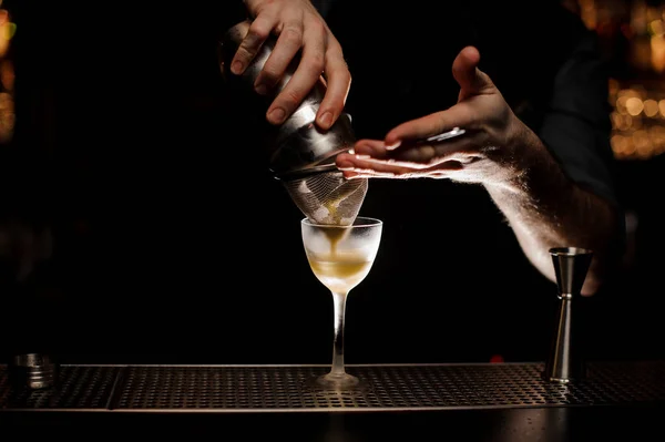 A kocsmáros egy alkoholos koktélt készítesz rázógéppel és szitával — Stock Fotó