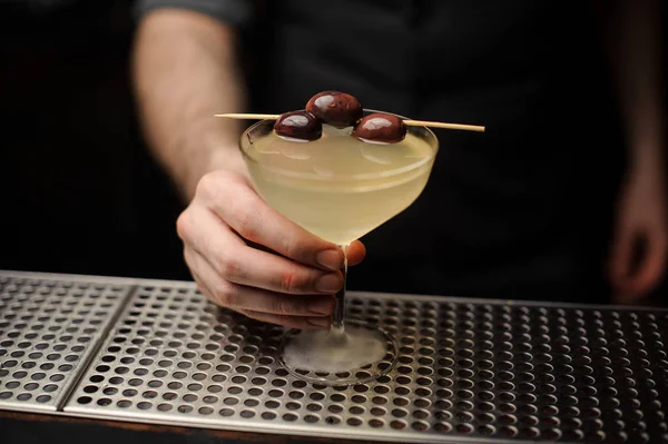 Cóctel de alcohol con aceitunas en mano de cantinero — Foto de Stock