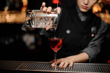 Barmen süzgeç ile cam kullanarak kokteyl yapar