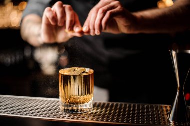 Barmen alkol kokteyl limon kabuğu sıkıyor