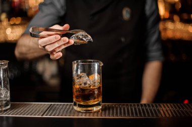 Barmen buz maşa ile cam buz koyar