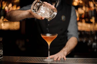 Barmen başka bir bardaktan cam buz ekleyerek