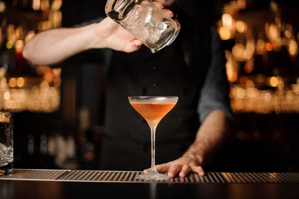 Bartender adds ice in glass from another glass — Stock Photo, Image