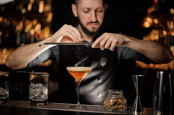 Cantinero con barba vertiendo cóctel de alcohol usando rallador —  Fotos de Stock