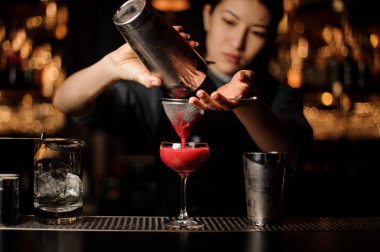 Kadın barmen shaker ve elek ile bir kokteyl dökme