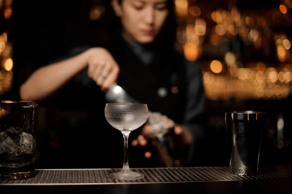 Female bartender preparing cocktail using shaker at bar counter