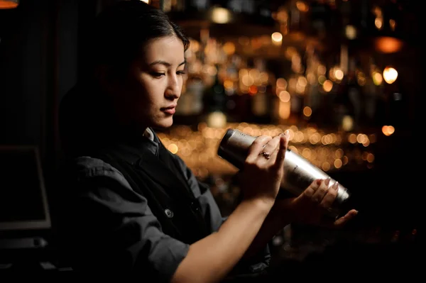 Женщина-бармен держит шейкер у барной стойки — стоковое фото