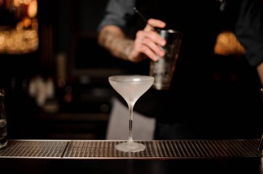 Barmen arka planda çalkalayıcı tutan barmen ile bar sayacı üzerinde cam yakın çekim