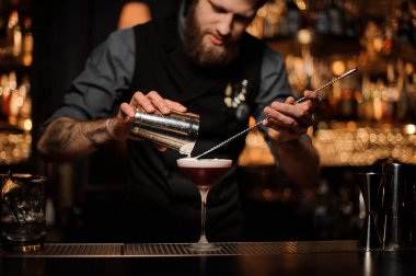 Erkek barmen shaker ve kaşık kullanarak kokteyl döker