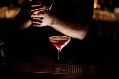 Barmen cam bir alkol kokteyl serpiştirir