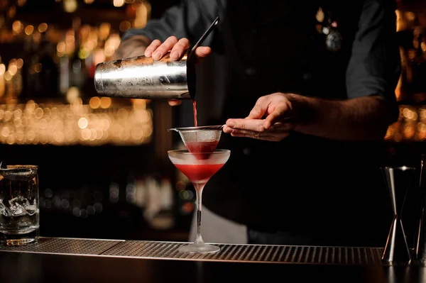 Bartender usa agitador e peneira para fazer coquetel — Fotografia de Stock