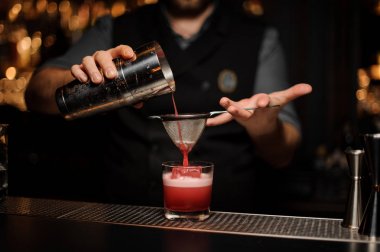 Barmen shaker ve elek kullanarak alkol içecek dökme