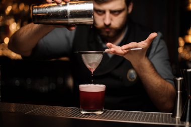 Barmen shaker ve elek ile bir alkol içecek yapar