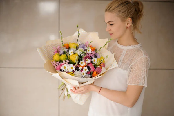 Blond meisje houdt een mooi boeket met madeliefjes — Stockfoto