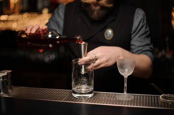 Varón camarero vierte bebida alcohólica con jigger — Foto de Stock