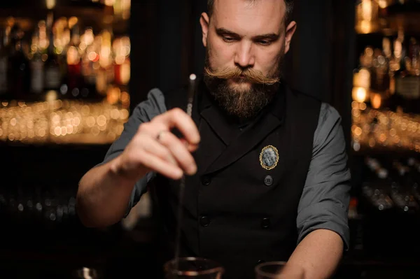 Bartender holds professional stirring spoon in bar