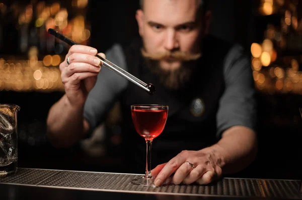 Ritratto di barista che lascia cadere la ciliegia in una bevanda alcolica — Foto Stock