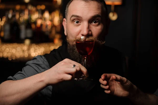 Male bartender sips alcohol cocktail in bar