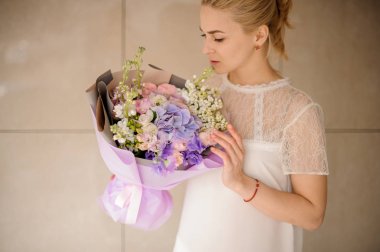 At kuyruklu sarışın kız mor ambalaj buket tutar