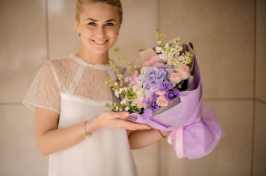 At kuyruklu gülümseyen kız mor ambalaj buket tutar