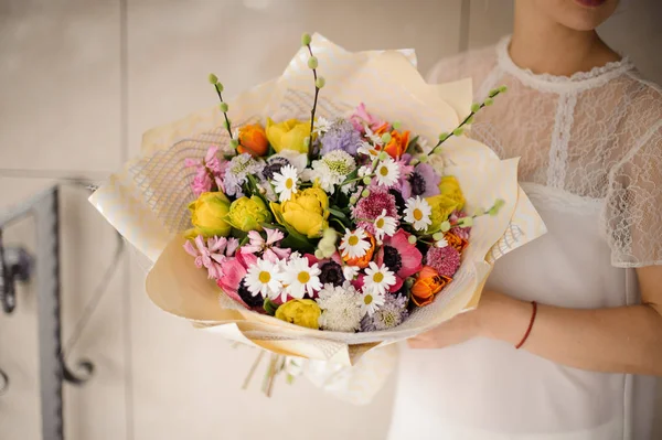 Mädchen mit einem Frühlingsstrauß aus zarten Blumen unterschiedlicher Farbe — Stockfoto