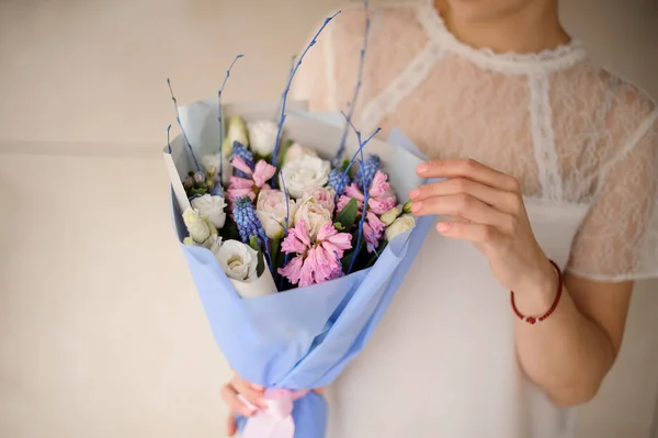 Jeune fille tenant un bouquet de printemps de fleurs blanches, roses et bleues tendres — Photo