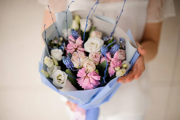 Fille en robe blanche tenant un bouquet de printemps de fleurs blanches, roses et bleues tendres — Photo