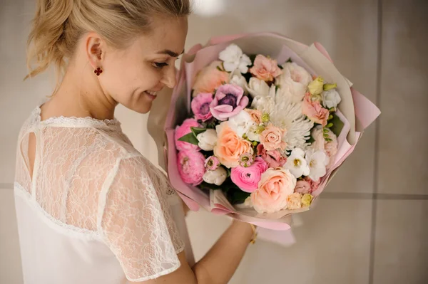 Chica sonriente sosteniendo un ramo de primavera de tiernas flores blancas y rosas — Foto de Stock