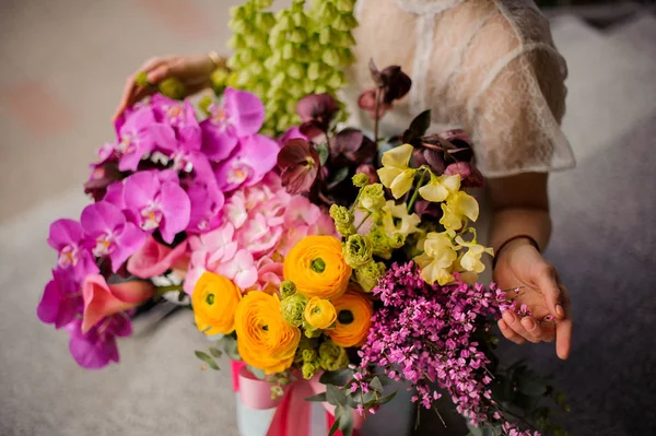 Menina sentada perto de uma caixa de primavera de flores concurso amarelo, verde e violeta — Fotografia de Stock