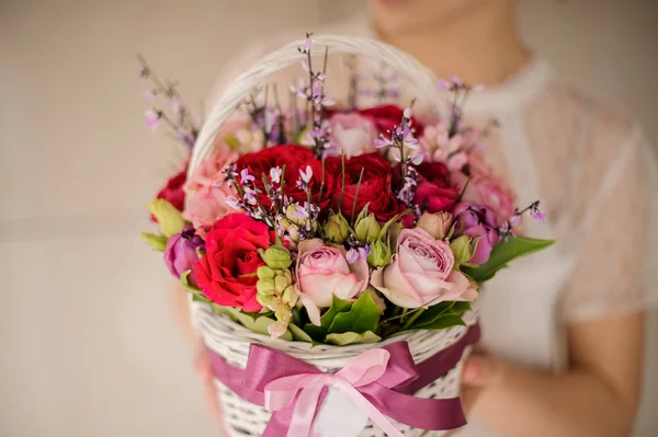 Menina segurando uma cesta branca primavera de rosas vermelhas e rosa — Fotografia de Stock