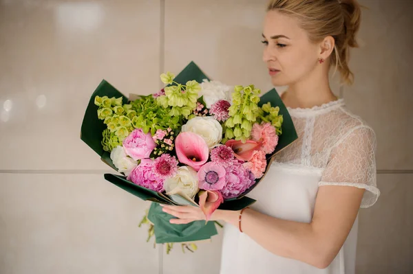 Menina loira jovem mantém buquê com várias flores — Fotografia de Stock