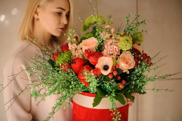 Menina segurando caixa de chapéu vermelho com flores — Fotografia de Stock