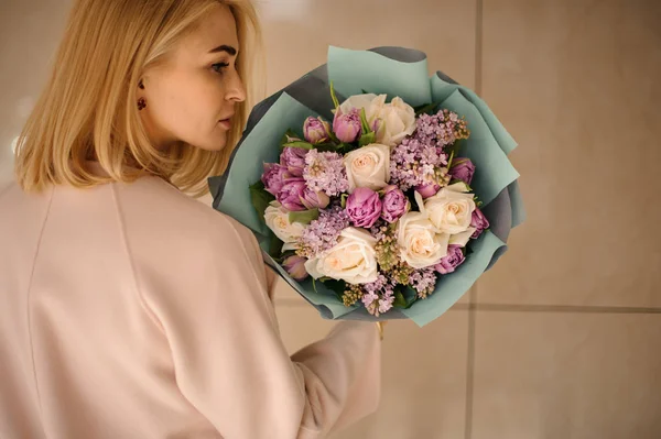 금발의 소녀는 보라색 꽃과 꽃다발 스탠드 — 스톡 사진