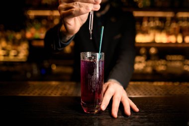 Barmen bir kokteyl yapmak için damlalık kullanır