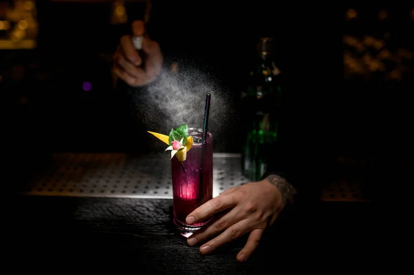 Barman schenkt cocktail versierd met bloem met sproeier — Stockfoto