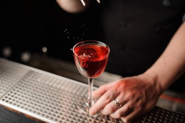 Profesyonel barmen kokteyl için cımbız ile bir kırmızı berry bir dekor ekleyerek